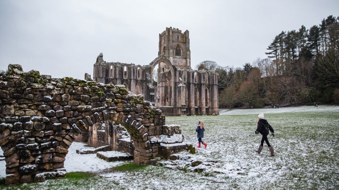 Children walking in a dusting of snow at Fountains Abbey